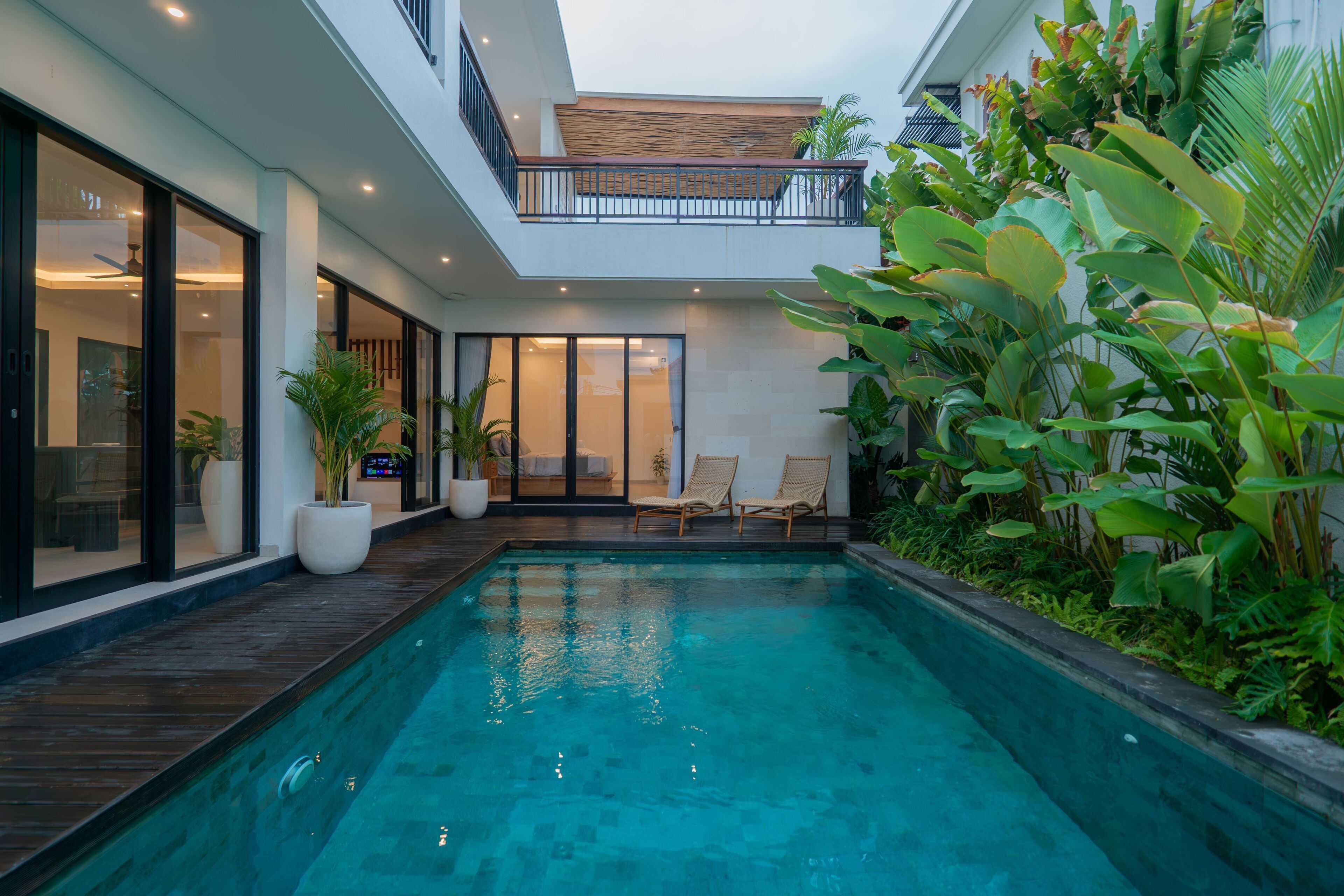 A modern house with a swimming pool, large windows, and a balcony.