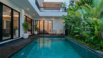 A modern house with a swimming pool, large windows, and a balcony.