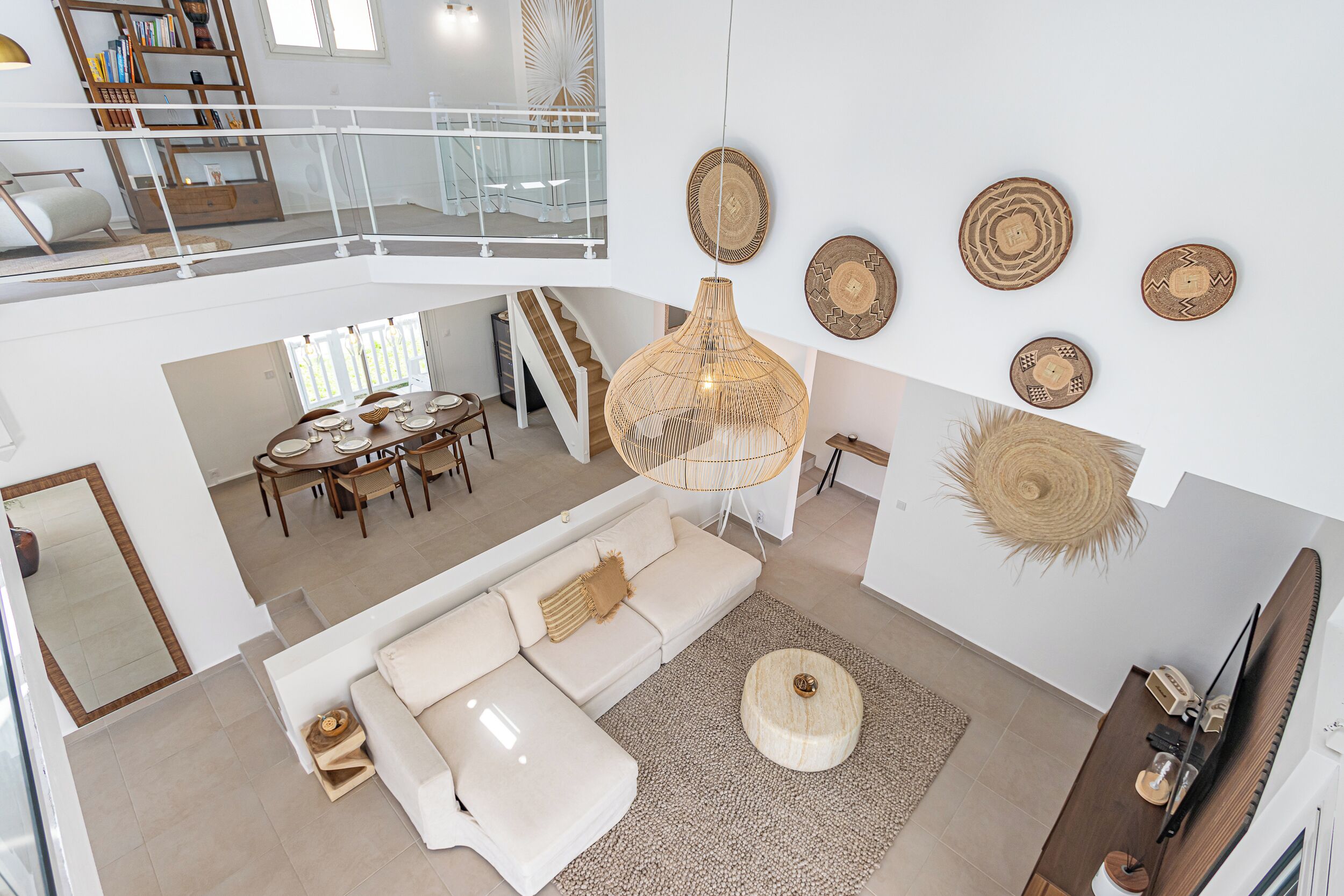 A spacious living area with a white sofa, a dining table, and a hanging light fixture.