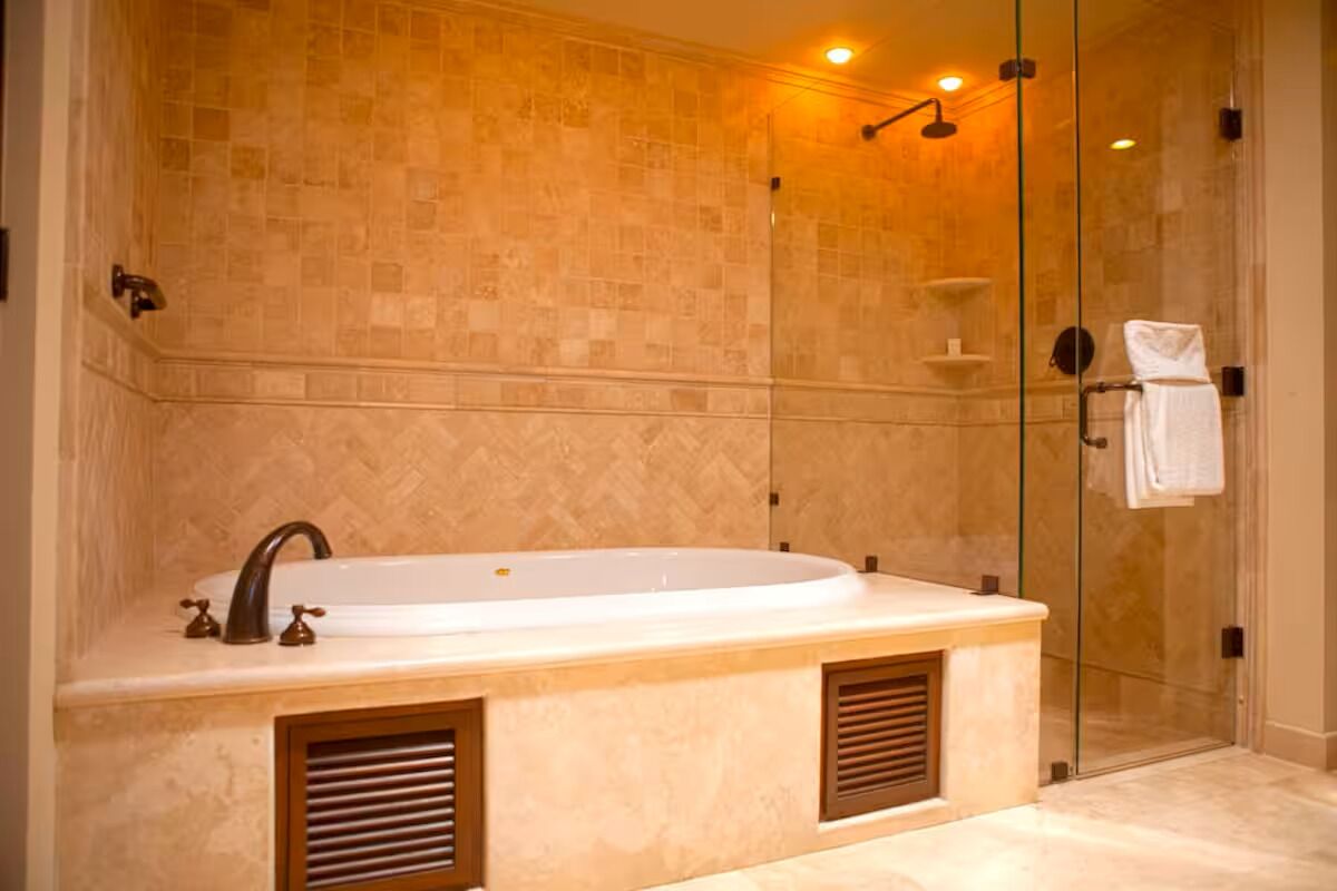 Un baño moderno con una bañera independiente, cabina de ducha con paredes de vidrio y pared revestida de mármol.