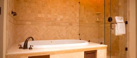 Un baño moderno con una bañera independiente, cabina de ducha con paredes de vidrio y pared revestida de mármol.