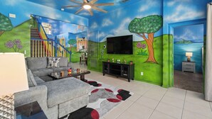 Ein Wohnzimmer mit Fernseher, Sofa und einer Treppe, die zur Küche führt.