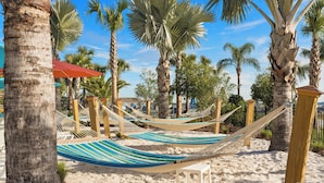 Una zona de playa con hamacas y palmeras.