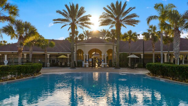 Ein Resort mit zentralem Pool, Palmen und einem überdachten Bereich mit Bögen.