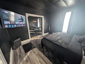 Habitación de hotel moderna con una cama grande, un televisor de pantalla plana en la pared y vista a la habitación contigua.