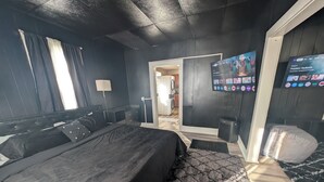 Ein modernes Hotelzimmer mit einem großen Bett, einem Flachbildfernseher und einem Kleiderschrank.