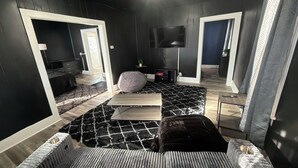 Ein modernes Zimmer mit Schwarz-Weiß-Farbgestaltung, einem großen Bett, einem Fernseher und einem einzigartigen geometrischen Teppich.