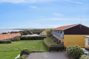 A residential building with a yellow exterior, a red roof, and a view of the sea. - Pension Koch, apartment 6 (Gudhjem)