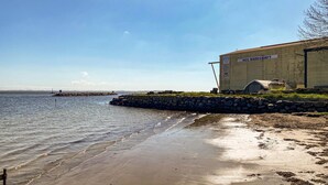 Un bâtiment situé sur la côte, avec une enseigne indiquant « HCC BADEVERFT », près d’une étendue d’eau calme.