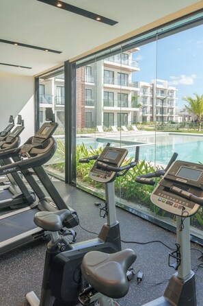 A gym with treadmills and a pool view. - Chic Tropical 1 BD APT near Downtown Punta Cana with AC and gym (Punta Cana)