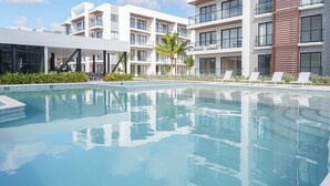 Un hotel modern amb piscina, múltiples balcons i una zona de jardí ben cuidada.