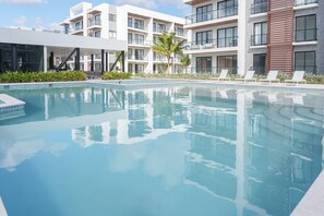 A modern hotel with a swimming pool, multiple balconies, and a well-maintained garden area. - Chic Tropical 1 BD APT near Downtown Punta Cana with AC and gym (Punta Cana)