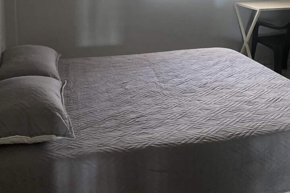 Una camera da letto con un letto, una ventola a soffitto, una finestra con tende e un condizionatore d'aria.