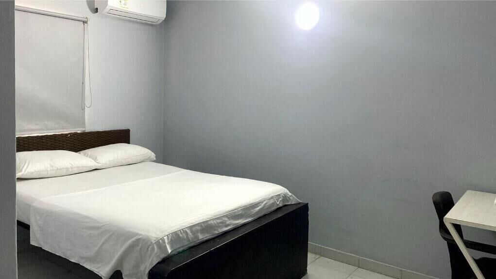 Una cama individual con ropa de cama blanca, cabecera de madera y una mesita pequeña a la derecha.