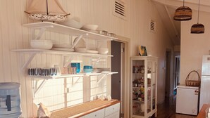 A kitchen with white cabinetry, a water dispenser, and a wooden countertop. - Beachfront Retreat at Rainbow Reef (Savusavu)