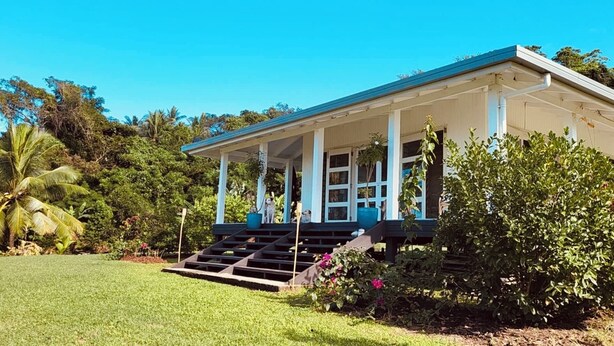 A two-story building with a covered porch and a staircase leading to the entrance. - Beachfront Retreat at Rainbow Reef (Savusavu)