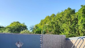 A rectangular hot tub with a wooden exterior and stone accents, surrounded by a low wall and lush greenery. - High villa - Swimming pool - 2 min plage de Vinty - Sainte-Rose (Sainte-Rose)