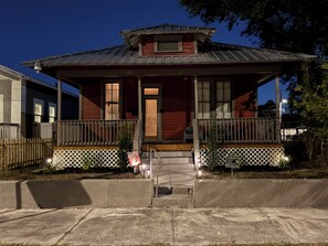 Uma casa de dois andares com varanda, porta da frente e um pequeno jardim frontal.
