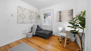 A modern, compact living space with a grey sofa, a white desk, and a large plant. - Centrally located, sleeps 5 outside Downtown Vancouver (Vancouver)