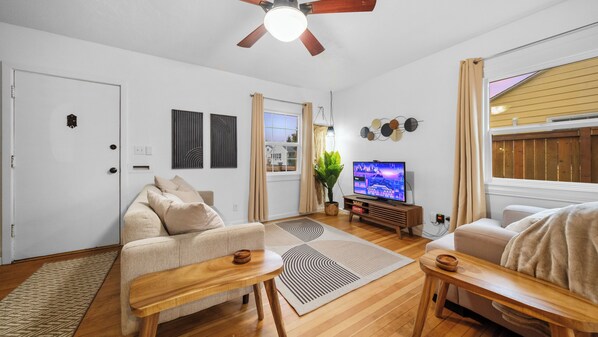 A modern living room with a sofa, a coffee table, a TV, and a ceiling fan. - Centrally located, sleeps 5 outside Downtown Vancouver (Vancouver)