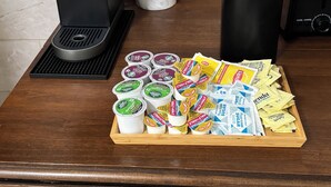 Un comptoir de cuisine avec une machine à café Keurig, un grille-pain, une plante en pot et un plateau contenant des dosettes de café et des sachets de sucre.