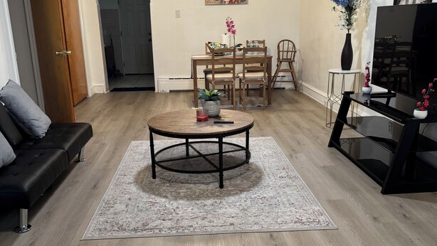 Un salon comprenant une table basse ronde, un canapé, un meuble pour la télévision et un coin repas avec des chaises et une table.