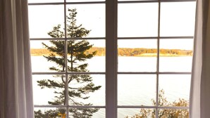 A room with a large window, a small table, and two chairs. - Storybook family cottage perched atop Penn Cove (coupeville)
