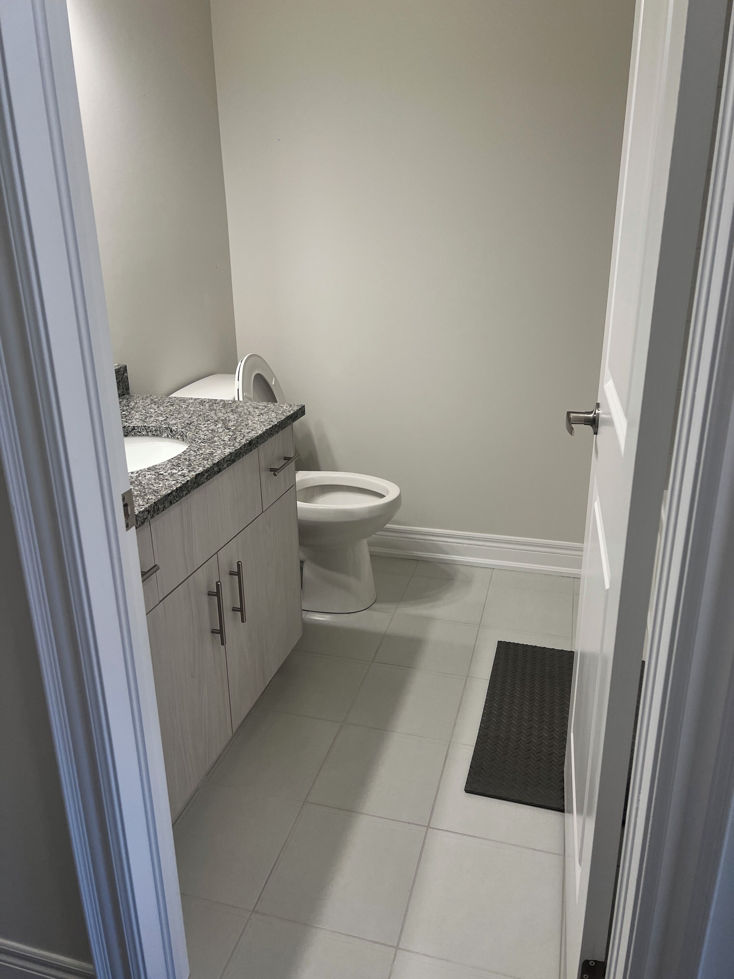 A bathroom with a toilet, sink, and cabinets.