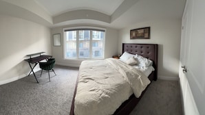 Quarto com cama grande, escrivaninha e janela.
