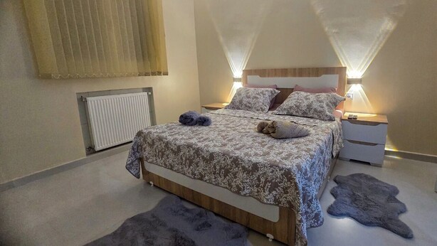 A bedroom with a bed, nightstands, a radiator, and a fur rug. - COMFORT in the heart of Algiers (Alger Centre)