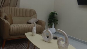 A modern living room with a beige sofa, a coffee table, decorative vases, and a potted plant. - COMFORT in the heart of Algiers (Alger Centre)