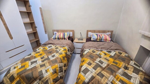 Ein Schlafzimmer mit zwei Betten, einem Kleiderschrank und einem kleinen Tisch mit einer Dekoration.