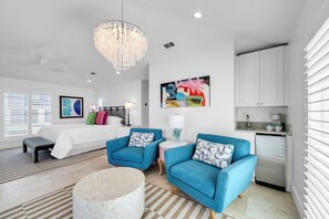 A modern living room with a white sofa, two blue armchairs, a round coffee table, and a chandelier. - 5BR Seagrove Beach Home on 30A~Pools, Bikes, Private Beach Access (Santa Rosa Beach)