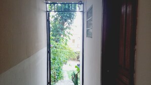 Un couloir avec un sol carrelé, un luminaire au plafond et une porte sur le côté droit.