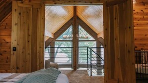 A wooden cabin with a sloped roof, a staircase leading to a balcony, and a bed in the foreground. - Lake Ida+Fish+Foosball+Bball+PingPong+Fire+Porch (Alexandria)