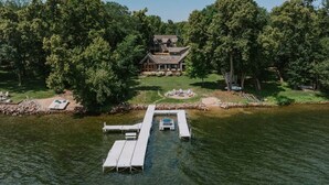 A lakeside property with a dock, a house surrounded by trees, and a small docked boat. - Lake Ida+Fish+Foosball+Bball+PingPong+Fire+Porch (Alexandria)