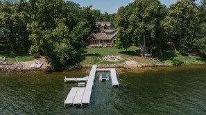 A lakeside property with a dock, a house surrounded by trees, and a small docked boat. - Lake Ida+Fish+Foosball+Bball+PingPong+Fire+Porch (Alexandria)