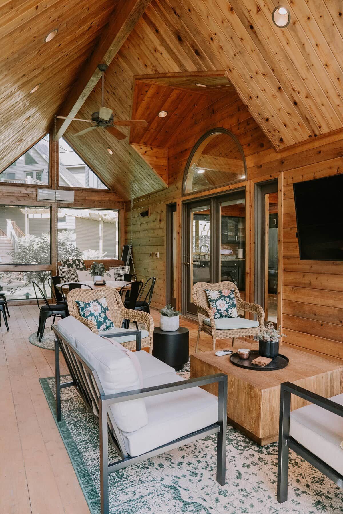 L’intérieur d’un chalet en bois chaleureux comprend un coin repas, des sièges et un téléviseur fixé au mur.