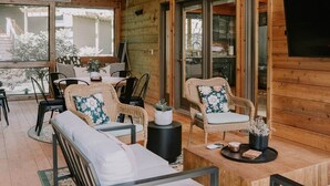 A cozy wooden cabin interior with a dining area, seating, and a TV mounted on the wall. - Lake Ida+Fish+Foosball+Bball+PingPong+Fire+Porch (Alexandria)