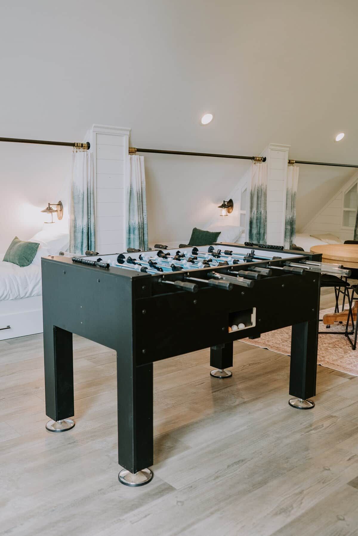 Una habitación moderna con mesa de futbolín, una cama y un comedor.