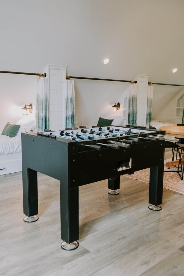 Een moderne kamer met een tafelvoetbaltafel, een bed en een eethoek.