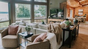 A spacious living room with a large TV, comfortable seating, and a view of the outdoors. - Lake Ida+Fish+Foosball+Bball+PingPong+Fire+Porch (Alexandria)