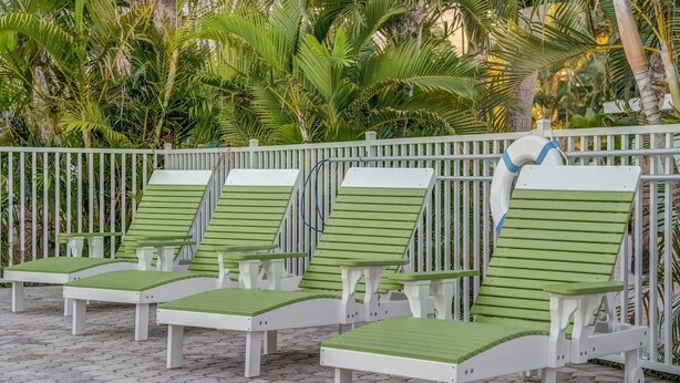 A row of green and white lounge chairs with a white railing in the background. - Stunning Queen Deluxe Suite close to Beaches, Restaurants, Shopping! (Sanibel)