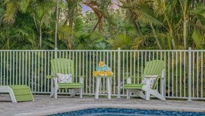 Un espace aménagé au bord de la piscine, avec deux chaises longues vertes et une petite table sur laquelle sont posées des serviettes.