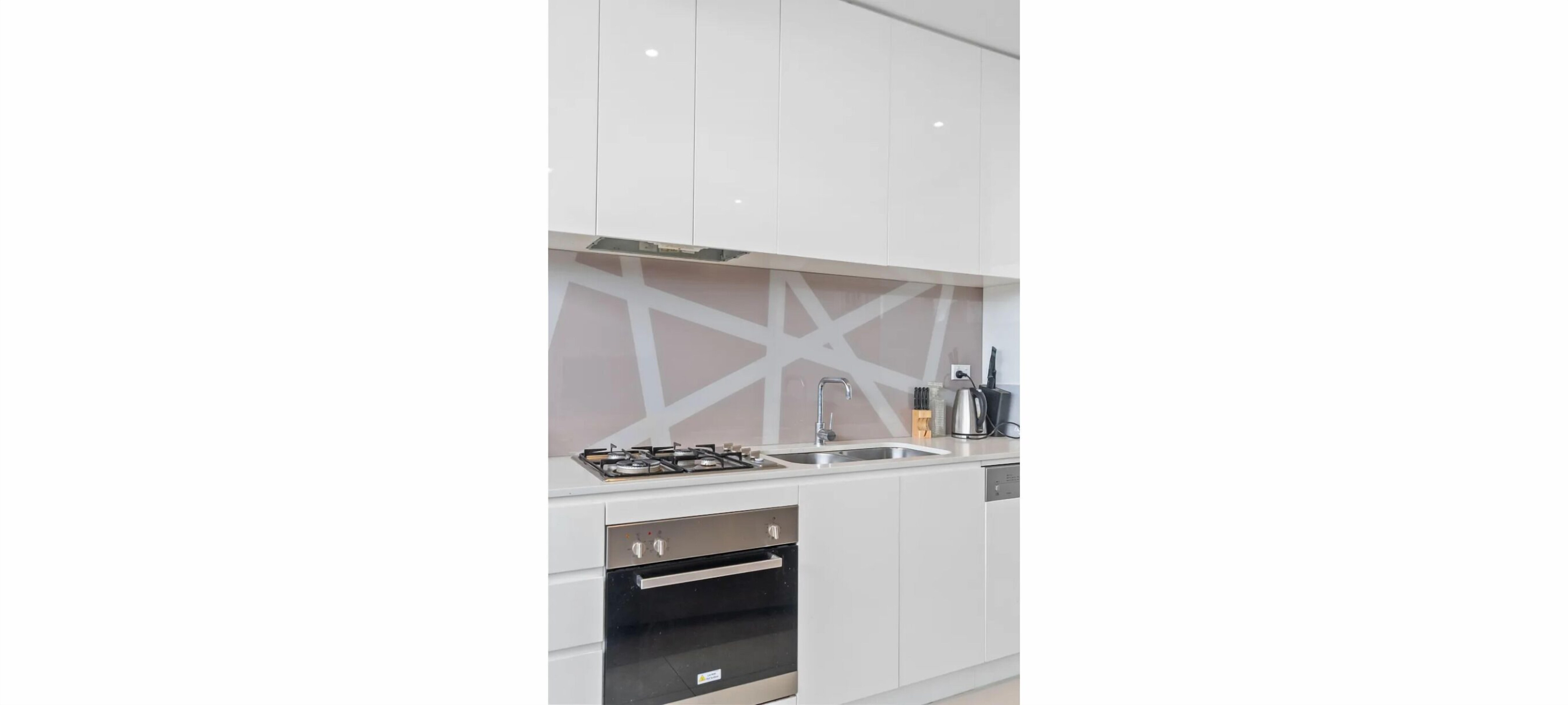 A modern kitchen with white cabinets, a gas stove, a sink, and a dishwasher.