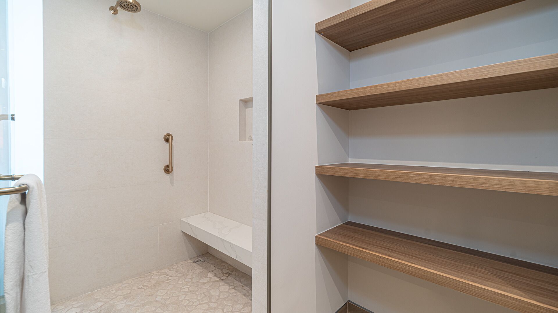 Une salle de bain avec une douche, un porte-serviettes et des étagères en bois.