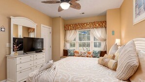 A bedroom with a bed, a dresser, a television, a ceiling fan, and a window with curtains. - Serene pool peaceful first floor kitchen washer dryer (Myrtle Beach)