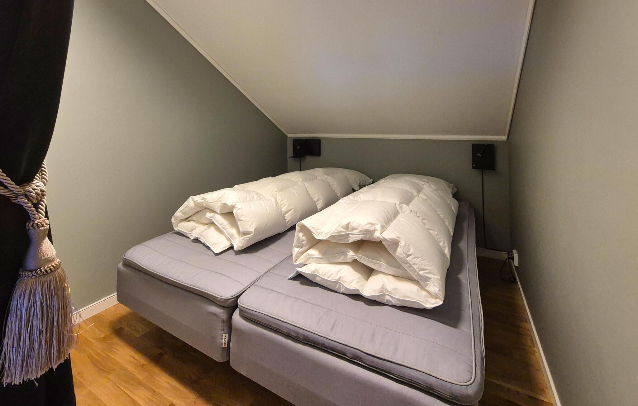 Habitació compacta amb un llit individual, una taula petita i televisió penjada a la paret.