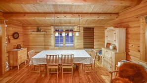 A wooden cabin interior with a dining table, chairs, a cabinet, and a window with curtains. - Beautiful home in Ljørdalen (Ljørdalen)