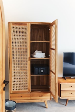 A wooden wardrobe with a woven front panel, a television on a wooden stand, and a small trash bin. - Villa KHAYA 2BR Private Pool Villa in Seminyak • Walk to Beach (Kabupaten Badung)